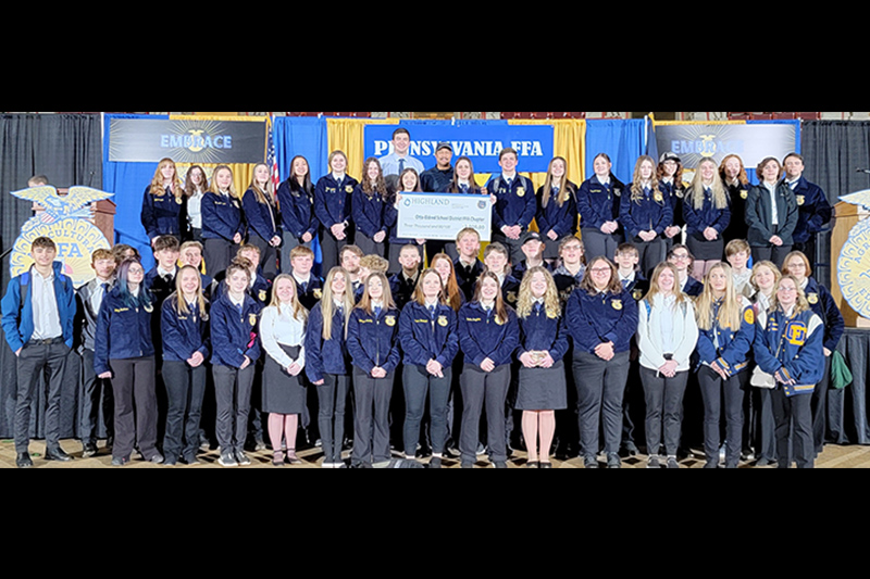 Group of AG students on stage wearing blue and holding up a check
