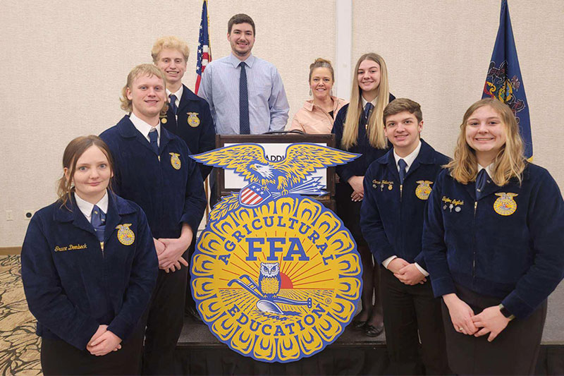 Students and teacher in uniform around the FFA Agricultural Education logo