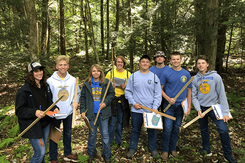 Group of happy AG students in the woods with rulers