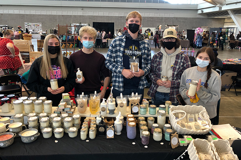 Group of masked students displaying candles and homemade goods